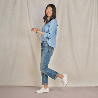 A woman in denim attire wearing casual white leather sneakers.
